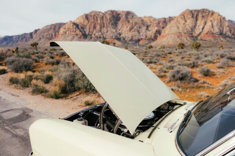 Car broken down on the side of the road with the hood open.